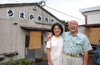 土岐さんの経営する製麺所「うまか食品」で肩を組むご夫婦